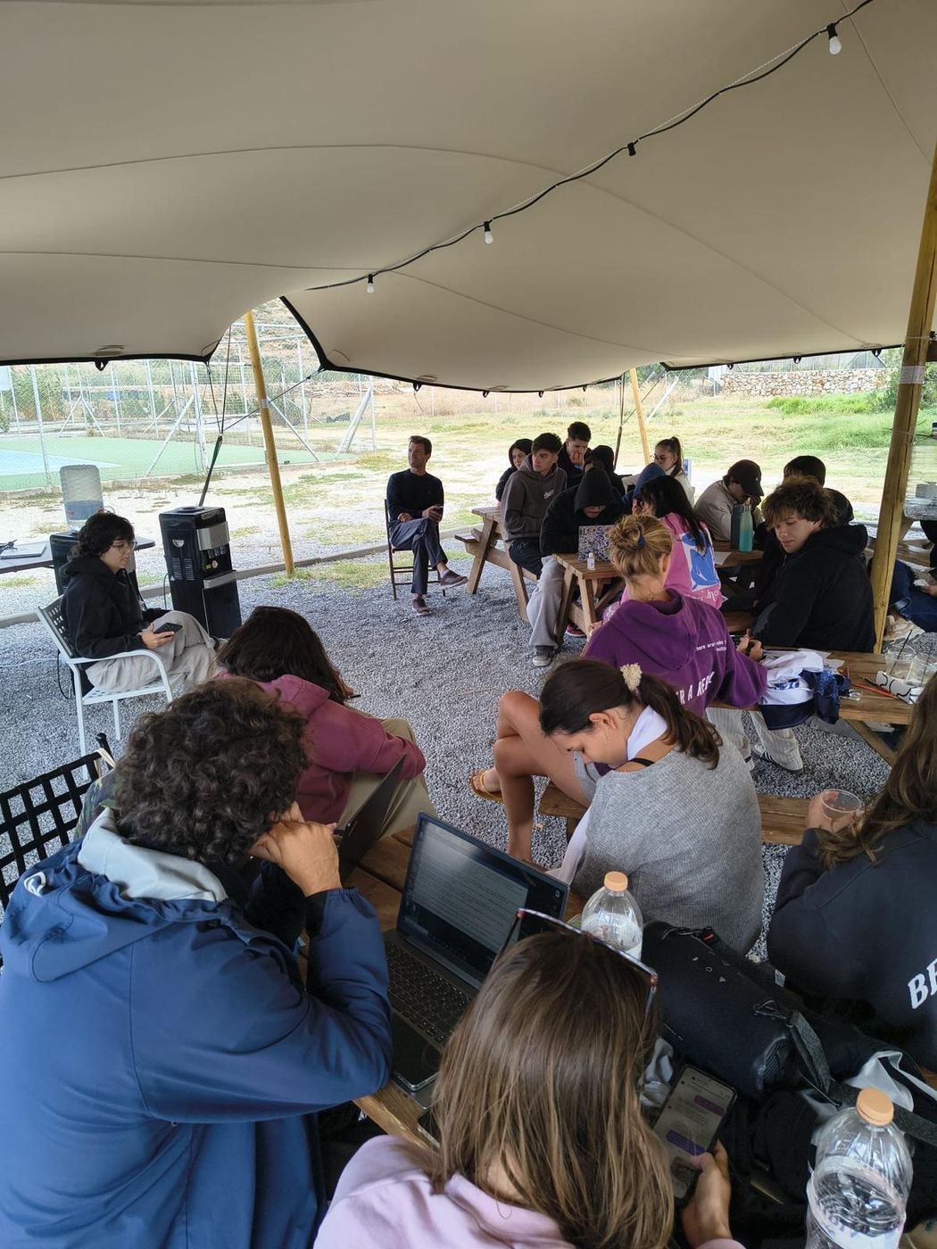 Participants working on laptops during a workshop under a tent